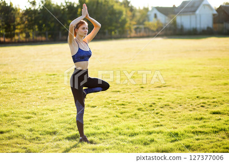 Young sportive woman doing yoga fitness exercises on warm summer day outdoors. Young sportive woman doing yoga fitness exercises on warm summer day outdoors. 127377006