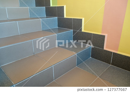 Wide staicase covered with ceramic tiles indoors in a house interior. Wide staicase covered with ceramic tiles indoors in a house interior. 127377087