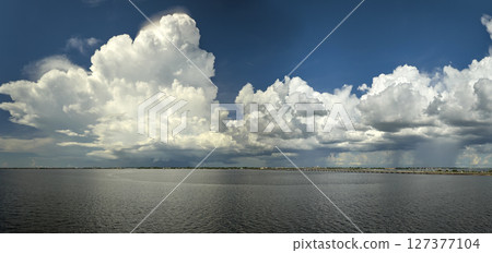 White fluffy cumulonimbus clouds forming from evaporating humidity of ocean water before thunderstorm on summer blue sky. Changing stormy cloudscape weather White fluffy cumulonimbus clouds forming from evaporating humidity of ocean water before thunderstorm on summer blue sky. Changing stormy cloudscape weather 127377104
