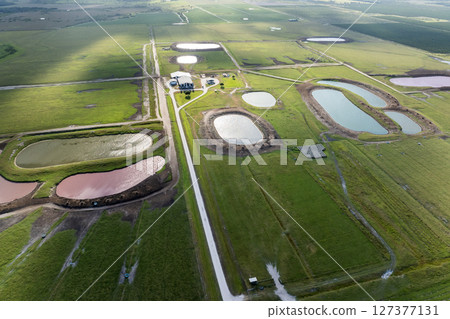Water reservoirs for cows grazing on green farm pasture. Drinking ponds at free range farm. Feeding of cattle on farmland grassland Water reservoirs for cows grazing on green farm pasture. Drinking ponds at free range farm. Feeding of cattle on farmland grassland 127377131