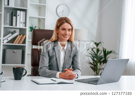 Busy by using laptop. Woman in business formal clothes is working in office Busy by using laptop. Woman in business formal clothes is working in office 127377180