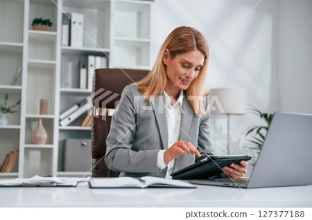 Using tablet. Woman in business formal clothes is working in office Using tablet. Woman in business formal clothes is working in office 127377188