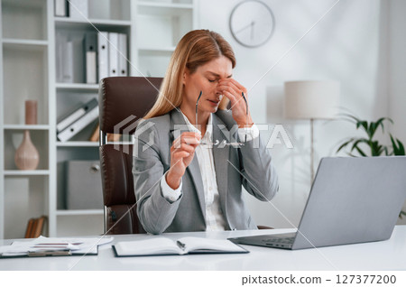 Tired, having headache. Woman in business formal clothes is working in office Tired, having headache. Woman in business formal clothes is working in office 127377200