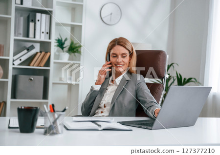 Talking by phone. Woman in business formal clothes is working in office 127377210