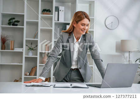 Standing by the table. Woman in business formal clothes is working in office 127377211
