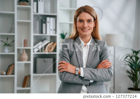 Standing with arms crossed. Woman in business formal clothes is working in office 127377214