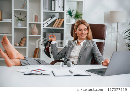 Sitting with legs on the table. Woman in business formal clothes is working in office Sitting with legs on the table. Woman in business formal clothes is working in office 127377239