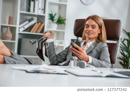 With legs on the table, resting. Woman in business formal clothes is working in office 127377242