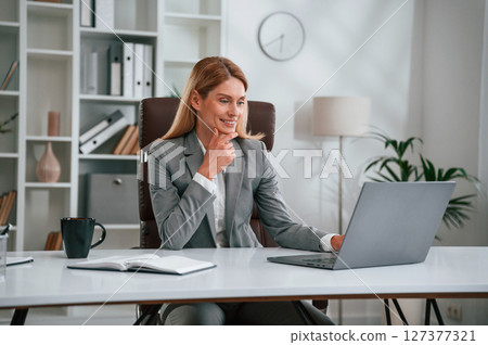 Busy by using laptop. Woman in business formal clothes is working in office 127377321