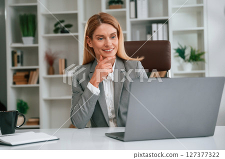 Busy by using laptop. Woman in business formal clothes is working in office 127377322