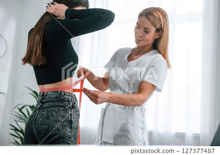 Measuring the waist. Young woman at a nutritionist's appointment. Medical care 127377487