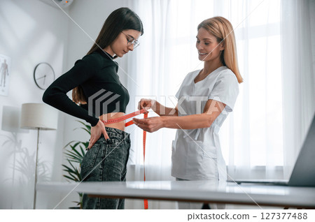 Measuring the waist. Young woman at a nutritionist's appointment. Medical care 127377488