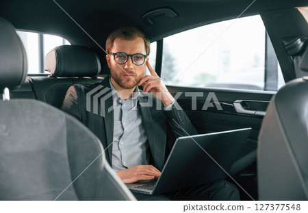 In comfortable modern automobile. Man in formal business clothes 127377548