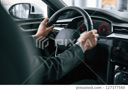 Driving the car. Man in formal business clothes is sitting in the modern automobile 127377560