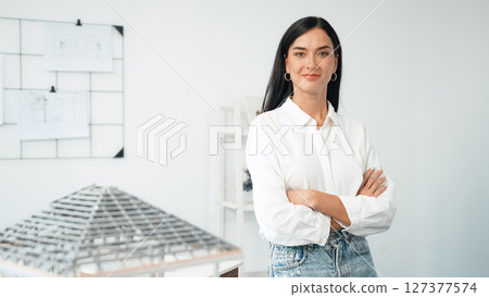 Young beautiful architect poses confidently with house model. Immaculate. Young beautiful architect poses confidently with house model. Immaculate. 127377574