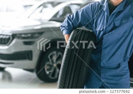 Tire replacement concept. Man in blue uniform is working in the car service Tire replacement concept. Man in blue uniform is working in the car service 127377692