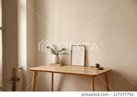 Vase with olive branches, old books. Cup of tea, coffee on table. Home office corner through open door. Empty wooden vertical picture frame mockup. Minimal Scandi interior. Beige wall background. Vase with olive branches, old books. Cup of tea, coffee on table. Home office corner through open door. Empty wooden vertical picture frame mockup. Minimal Scandi interior. Beige wall background. 127377792