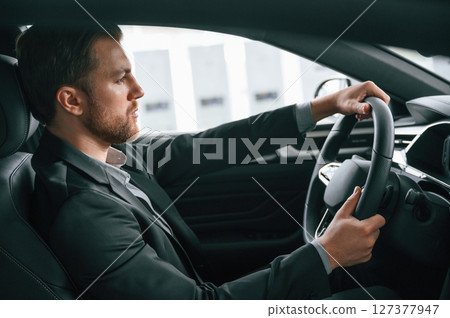 Test drive. Man in formal business clothes is sitting in the modern automobile 127377947
