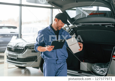 With box and notepad. Man in blue uniform is working in the car service 127377971