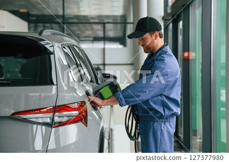 Testing the fuel system. Man in blue uniform is working in the car service Testing the fuel system. Man in blue uniform is working in the car service 127377980