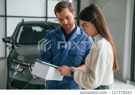 Young woman is visiting auto mechanic in garage. Repair service Young woman is visiting auto mechanic in garage. Repair service 127378042
