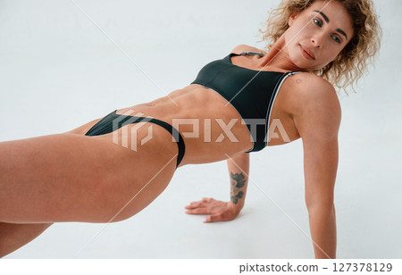On the hands and legs. On the floor. Young caucasian woman with athletic body shape is indoors at daytime On the hands and legs. On the floor. Young caucasian woman with athletic body shape is indoors at daytime 127378129