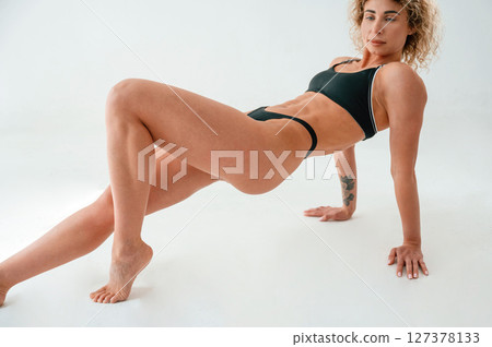 On the hands and legs. On the floor. Young caucasian woman with athletic body shape is indoors at daytime 127378133