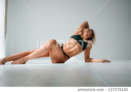 In sportive underwear. On the floor. Young caucasian woman with athletic body shape is indoors at daytime 127378180