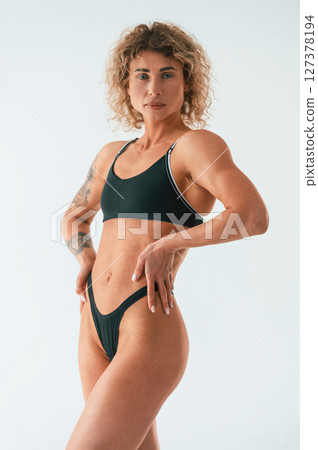 Hands on the waist, standing. Young caucasian woman with athletic body shape is indoors at daytime Hands on the waist, standing. Young caucasian woman with athletic body shape is indoors at daytime 127378194