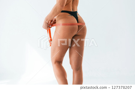 Back is being measuring by the tape. Young caucasian woman with athletic body shape is indoors at daytime 127378207