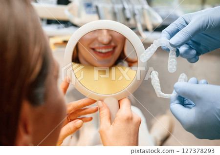 Woman in the stomatology clinic, visiting dentist, installing the aligner Woman in the stomatology clinic, visiting dentist, installing the aligner 127378293