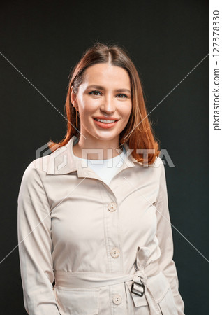 Young woman with aligner is standing against black background 127378330