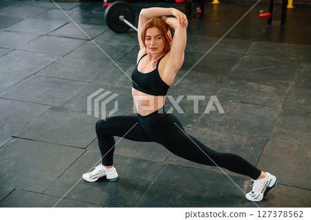 Stretching the legs. Beautiful strong woman is in the gym Stretching the legs. Beautiful strong woman is in the gym 127378562