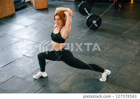 Stretching the legs. Beautiful strong woman is in the gym 127378563
