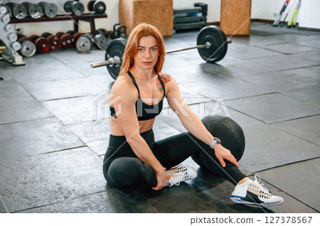 Sitting on the floor. Beautiful strong woman is in the gym Sitting on the floor. Beautiful strong woman is in the gym 127378567
