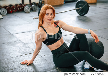 Sitting on the floor. Beautiful strong woman is in the gym 127378568