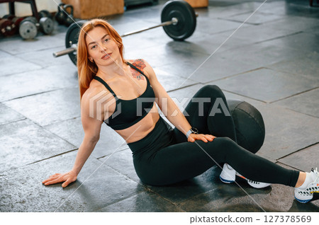 Sitting on the floor. Beautiful strong woman is in the gym Sitting on the floor. Beautiful strong woman is in the gym 127378569