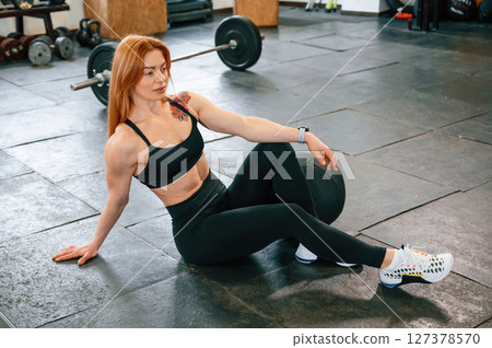 Sitting on the floor. Beautiful strong woman is in the gym Sitting on the floor. Beautiful strong woman is in the gym 127378570