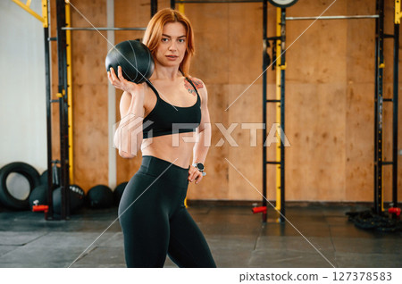 Holding ball. Beautiful strong woman is in the gym Holding ball. Beautiful strong woman is in the gym 127378583