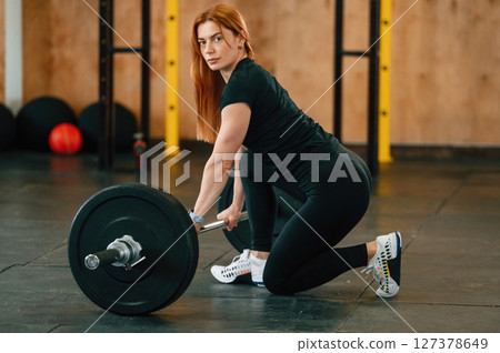 Sitting with barbell on the floor. Beautiful strong woman is in the gym Sitting with barbell on the floor. Beautiful strong woman is in the gym 127378649