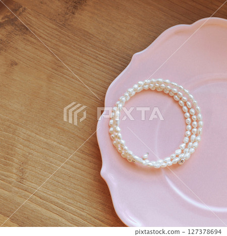 Large pearl necklace on pink ceramic plate and wooden floor background Large pearl necklace on pink ceramic plate and wooden floor background 127378694