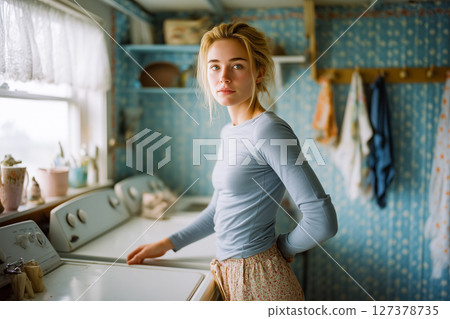 A woman stands in front of a washing machine 127378735