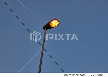 Lamp post on a street glowing at dusk 127378852