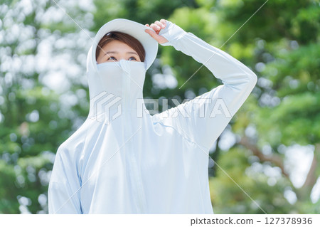 一名女子穿著防曬衣來保護自己免受紫外線的傷害 一名女子穿著防曬衣來保護自己免受紫外線的傷害 127378936