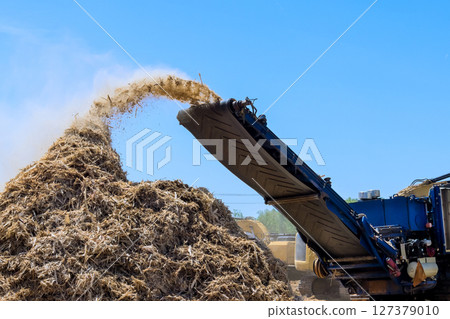 Large equipment distributes organic material at wood chip industrial activity in land clearing for construction 127379010