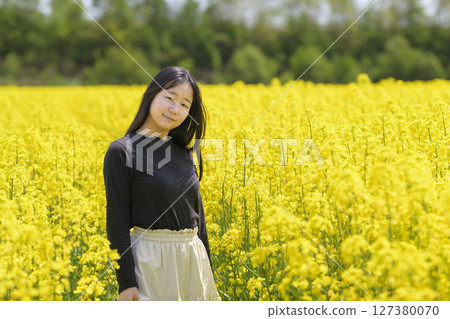 A woman sightseeing in a field of rapeseed flowers in full bloom 127380070