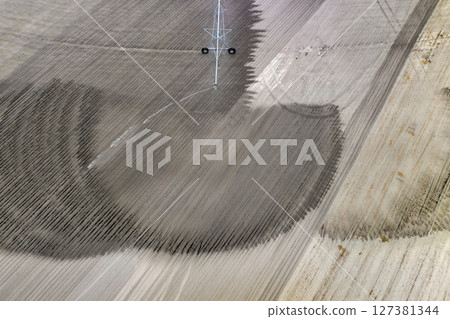Spraying water on farmland ground for crop growth during period of drought. Sprinkler irrigation system watering farm field during dry season 127381344