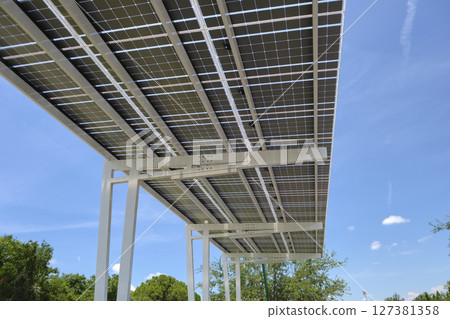 Solar panels installed as shade roof over parking lot for parked electric cars for effective generation of clean electricity. Photovoltaic technology integrated in urban infrastructure 127381358