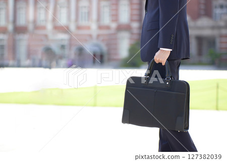 A young businessman in a suit walking through a business district 127382039