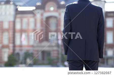 The back of a young businessman in a suit standing in a business district 127382087